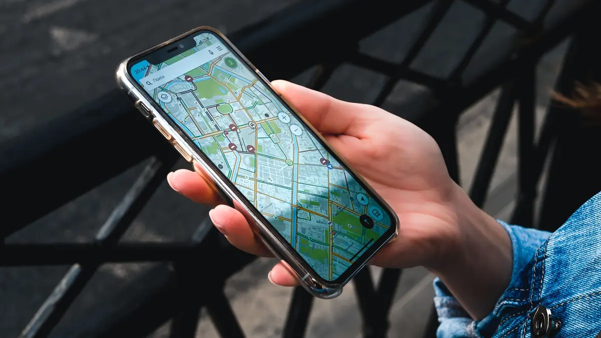 A hand holds a phone showing a street map of a neighborhood.