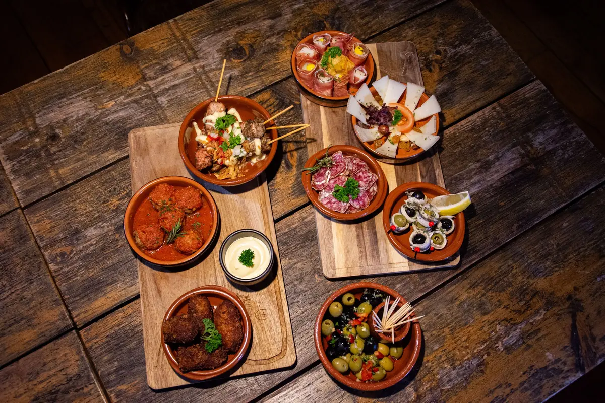 A spread of small plates shared on one restaurant table, seen from above.