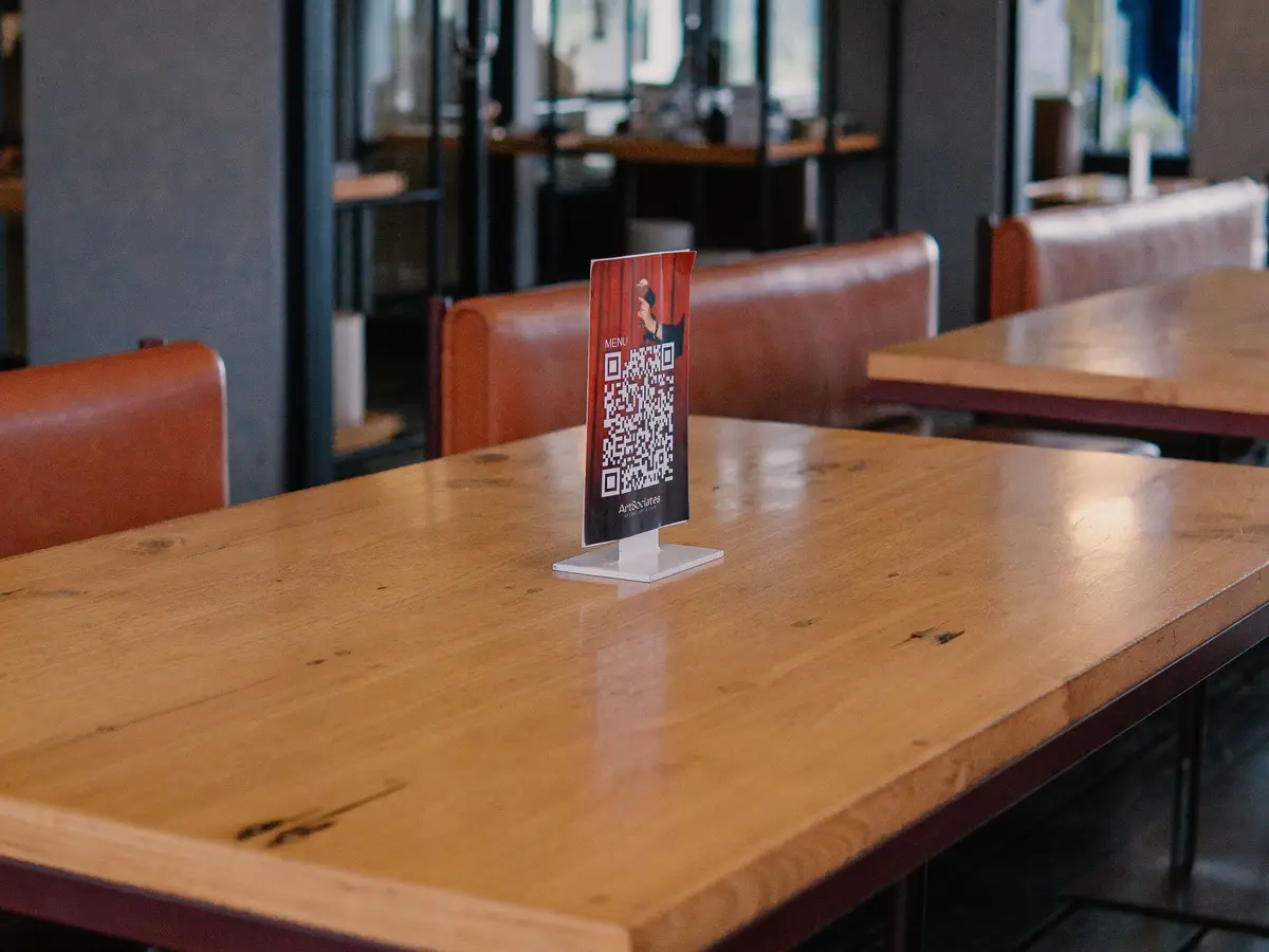 A printed QR code card in a small stand on an empty restaurant table.