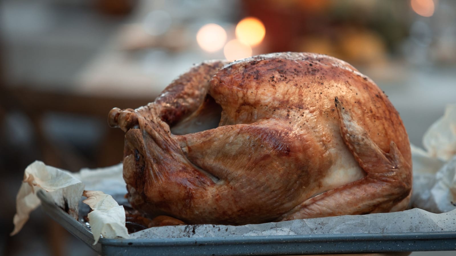 A whole roast turkey on a sheet tray, the centerpiece of a Thanksgiving to-go order before it is carved and packed.